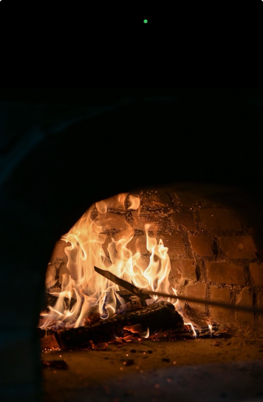 Flames and glowing logs inside a brick oven