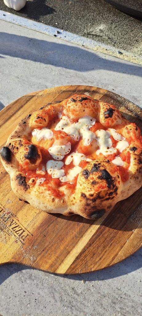 Fresh pizza with a golden, airy crust on a wooden peel