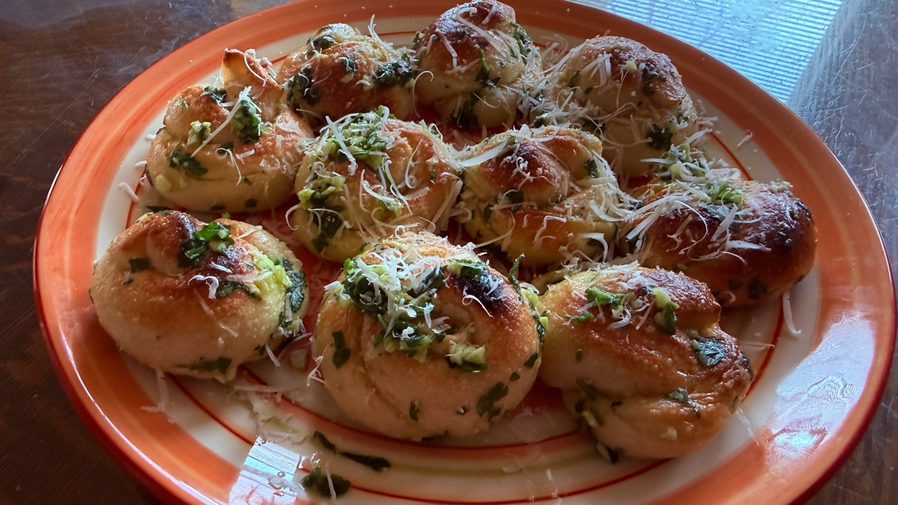 Golden garlic knots topped with herbs and grated cheese